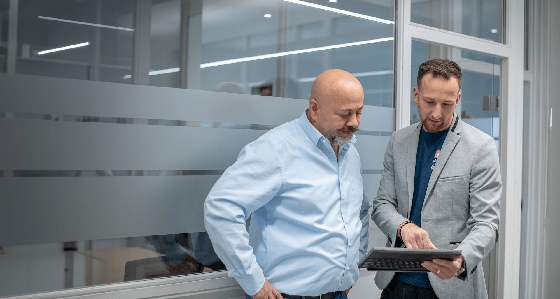 Zwei Geschäftsmänner in einem modernen Büro bei einer Besprechung mit Tablet